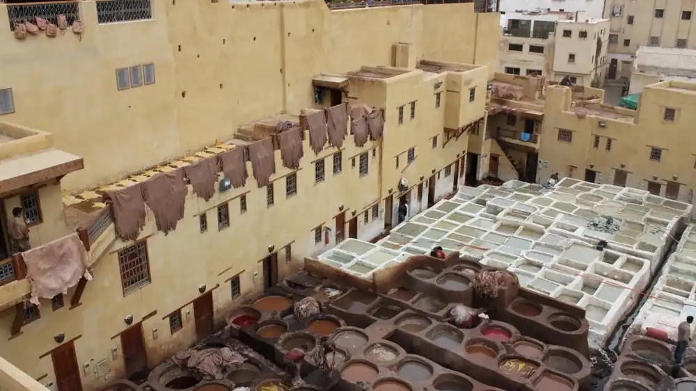 Curtiembre tradicional vista desde una terraza: piletas de cal y de tanino entre paredes de adobe, con cueros colgados a secar